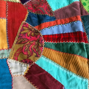 May include: A white ceramic mug with a black handle and the text "But First, Coffee" in a bold, black font. The mug is set against a blurred background, suggesting a cosy setting.