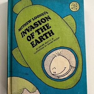 May include: A vintage children's book titled "Matthew Looney's Invasion of the Earth." The cover features a green spaceship with a smiling cartoon character inside, set against a blue background. The book's title is in large, bold letters.