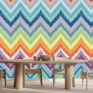 Puede incluir: Un mural colorido con un vibrante patrón de chevrón en tonos de azul, verde, amarillo, naranja y morado. Una mesa de comedor de madera con sillas está frente al mural. La habitación tiene luz natural de una ventana.