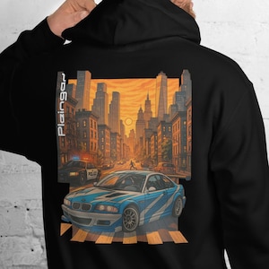 May include: Black hoodie with a graphic of a blue car on a crosswalk in a city scene. The design includes a cityscape with tall buildings and a sunset. The text "Plaingo" is printed vertically on the left side.