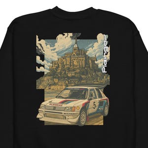 Peut inclure: Sweat-shirt noir avec un imprimé graphique. L'imprimé présente une voiture de rallye blanche et bleue avec le numéro 5, un bâtiment historique et le texte "Plein Gaz". Le design a un style vintage et illustré.