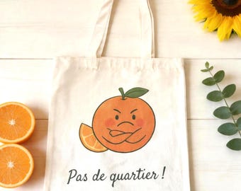 Può includere: Una borsa tote in tela color crema con la grafica di un'arancia dall'espressione imbronciata, con le braccia incrociate e una foglia verde. Accanto al personaggio c'è uno spicchio d'arancia. Sotto la grafica, il testo Pas de quartier! in nero.