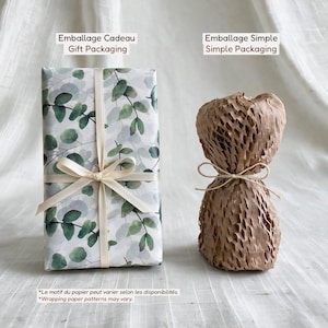 May include: Two packaging options: a rectangular gift box wrapped in white paper with a green eucalyptus leaf pattern and a cream ribbon, and a brown honeycomb paper wrap tied with twine. Text labels read Emballage Cadeau Gift Packaging and Simple.