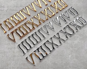 May include: Two sets of Roman numeral charms, one in gold tone and one in silver tone. Each set includes the numerals I through XII, featuring a stylized, serif-inspired font with a polished metallic finish, arranged in two distinct rows.