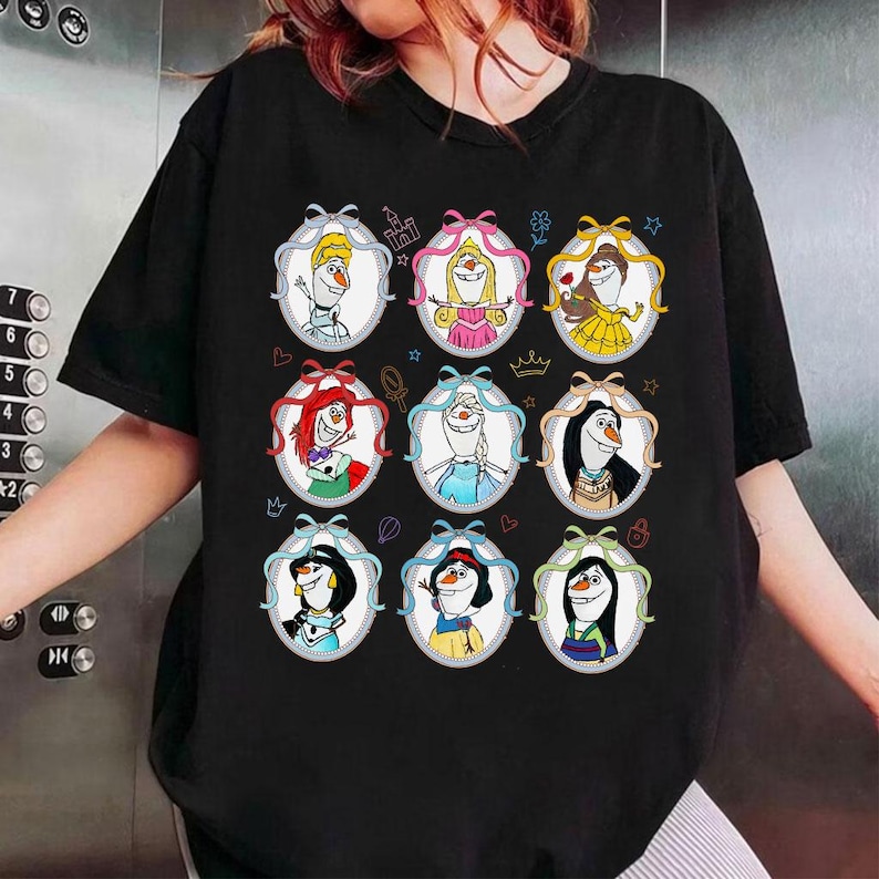 May include: Black t-shirt featuring nine oval portraits of cartoon characters, each framed with a ribbon. The portraits depict characters with various hairstyles and outfits, set against a white background.