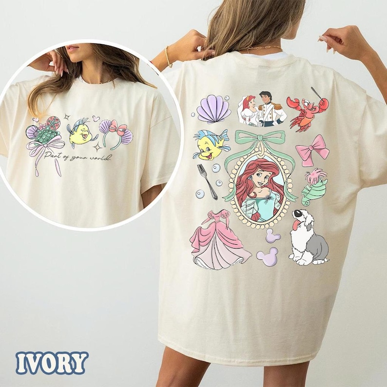 May include: Ivory-colored t-shirt featuring colorful cartoon graphics from a popular animated film. The front has a design with text, while the back showcases various characters and elements from the movie. The shirt is a comfortable, casual style.