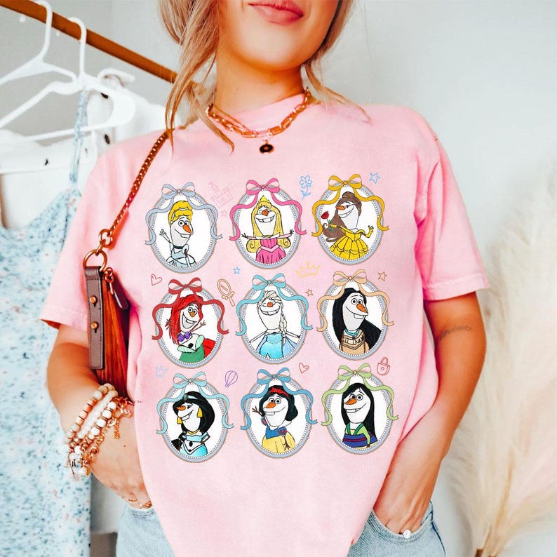 May include: Pink t-shirt featuring nine framed cartoon images of characters. Each image is a cartoon character with a bow and ribbon. The shirt is a light pink color and has a casual fit.