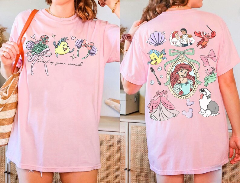 May include: Pink t-shirt featuring colorful cartoon graphics of characters and elements from a popular animated movie. The front of the shirt has the text "Part of your world". The back of the shirt has additional graphics.