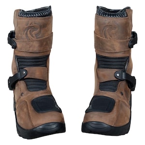 May include: Pair of brown leather motorcycle boots with black detailing. The boots feature buckles, reinforced panels, and a textured design. The soles are black, and the boots appear robust and protective.