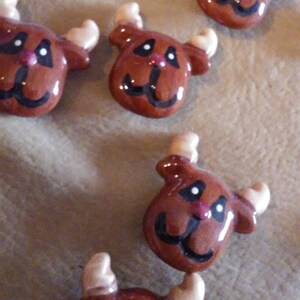 May include: Four brown ceramic reindeer ornaments with white antlers and black painted eyes, noses, and mouths.