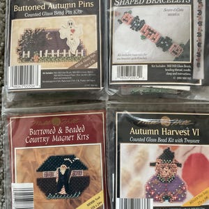 以下が含まれることがあります： Mill Hillの密封された4つのクラフトキットが表示されています。キットには、ボタン付きの秋のピン、形作られたブレスレット、ボタンとビーズのカントリーマグネット、秋の収穫シーンを作成するための材料が含まれています。各キットはユニークなデザインです。