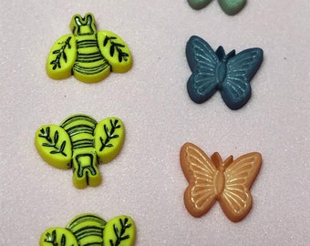 Peut inclure: Assortiment de boutons en forme d'abeille jaune et de papillon coloré. Les boutons sont en plastique et ont une finition brillante.