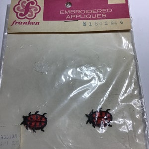 May include: A package of two embroidered red and black ladybug appliques. The package is labeled "Embroidered Appliques" and "W1862 Col 4".