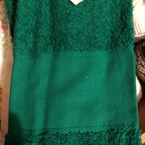 Puede incluir: Una toalla de mano verde con una superficie texturizada. La toalla tiene un borde tejido.