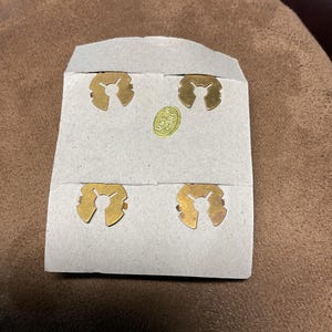 May include: Four gold-coloured metal clips on a white card with the text "Made in China".