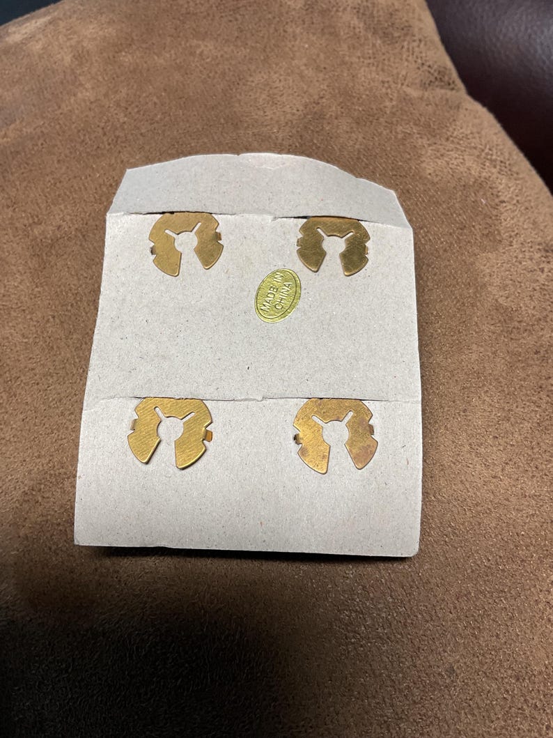May include: Four gold-coloured metal clips on a white card with the text "Made in China".