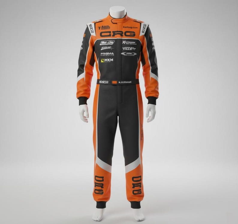 May include: Orange and black racing suit with white accents, displayed on a mannequin. The suit features the "CRG" logo and other sponsor logos. The suit has a black collar and cuffs, with the name "N. SURNAME" printed on the belt.