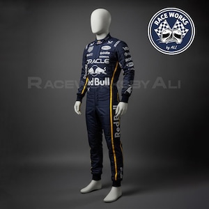 May include: A navy blue racing suit with yellow stripes and sponsor logos, including "Red Bull" and "Oracle." The suit is displayed on a mannequin. The image also includes a circular logo with checkered flags and the text "Race Works by ALI."