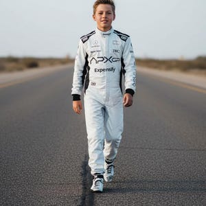 May include: A young person in a white racing suit with black accents, walking on a paved road. The suit features sponsor logos and the text "APXGP" and "Expeinsify". The person is wearing white racing shoes.