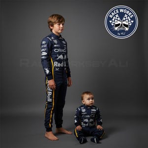 May include: Two children's racing suits in navy blue with yellow accents. The suits feature sponsor logos and the text "Red Bull" and "Oracle". The suits are designed for different sizes, one for a child and one for a baby.