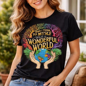 May include: Black t-shirt with the text "AND I THINK TO MYSELF What a WONDERFUL WORLD" in gold and white. The design features a colorful tree and a globe held in hands.