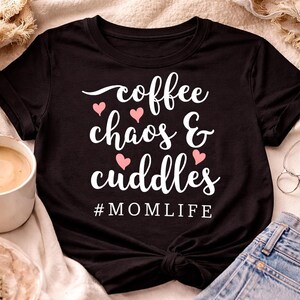 Può includere: Una tazza di ceramica bianca con un manico nero e la scritta "But First, Coffee" in stile scritto a mano. La tazza è su una superficie bianca. La tazza è alta circa 10 cm.