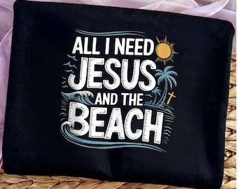 May include: Black tote bag with the text "ALL I NEED JESUS AND THE BEACH" in white and blue. The design includes a sun, palm trees, waves, and a cross. The bag is on a woven surface.