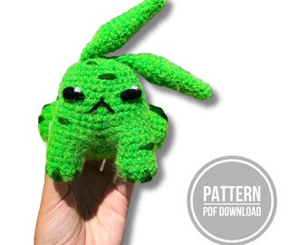 May include: A bright green crocheted creature with long ears, dark embroidered eyes, and a small mouth. The textured yarn body features darker green spots. A circular graphic in the corner displays the text PATTERN PDF DOWNLOAD in white letters.