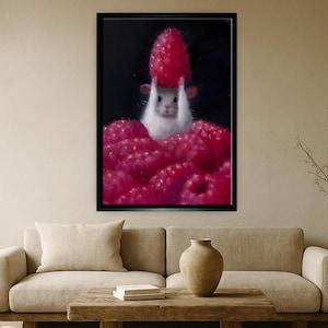 May include: A framed art print featuring a white mouse holding a large red raspberry above its head. The mouse is surrounded by a pile of bright red raspberries against a black background. The artwork is displayed in a black frame.