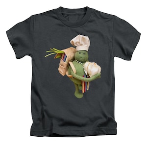 May include: Dark grey t-shirt featuring a green turtle chef character wearing a white chef's hat. The turtle carries a bag of spring onions and a head of garlic. The turtle has a colourful striped apron.