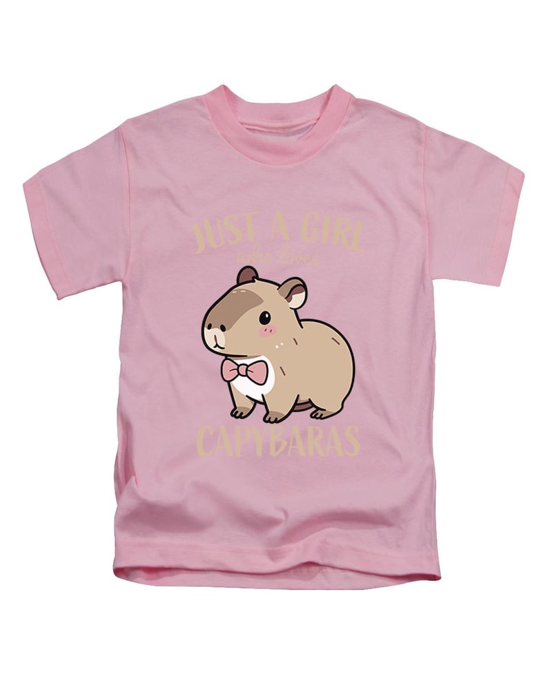 May include: Pink t-shirt featuring a cartoon capybara wearing a pink bow tie. The text "JUST A GIRL who loves CAPYBARAS" is printed above and below the capybara illustration. The shirt has short sleeves and a crew neck.
