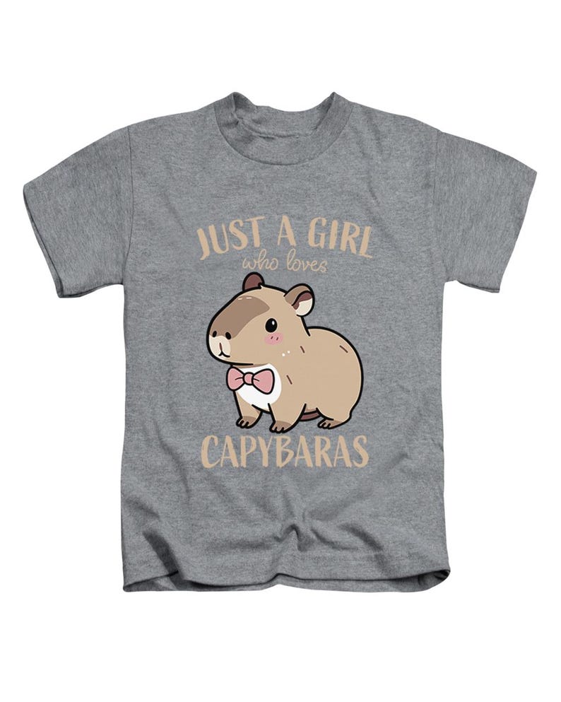 May include: A gray t-shirt featuring a cartoon capybara wearing a pink bow tie. The text "JUST A GIRL who loves CAPYBARAS" is printed above and below the capybara illustration. The shirt is designed for kids.