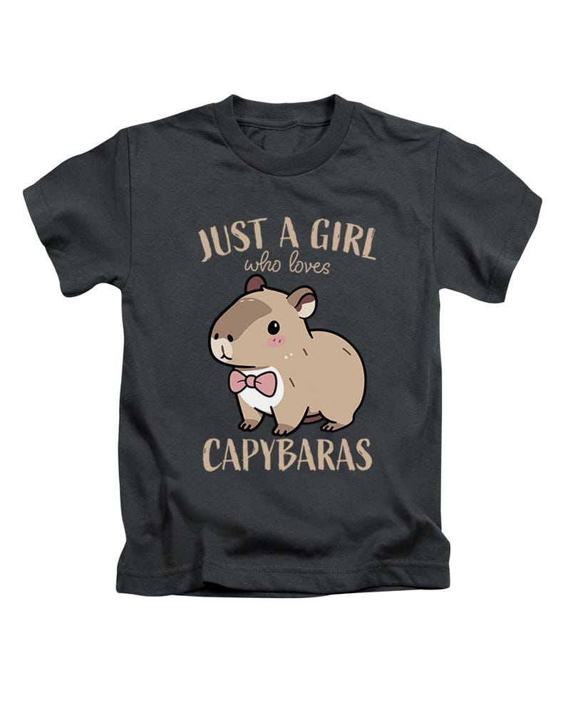 May include: Dark gray t-shirt featuring a cartoon capybara with a pink bow tie. The text reads "JUST A GIRL who loves CAPYBARAS" in a light brown color. The shirt is a crew neck style.