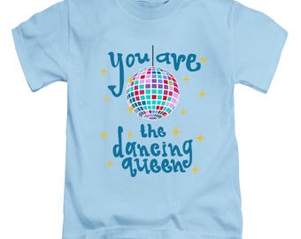 Może przedstawiać: Jasnoniebieska koszulka z napisem "you are the dancing queen" w turkusowym skrypcie. Wielokolorowa grafika kuli dyskotekowej znajduje się nad tekstem, z żółtymi gwiazdkami.