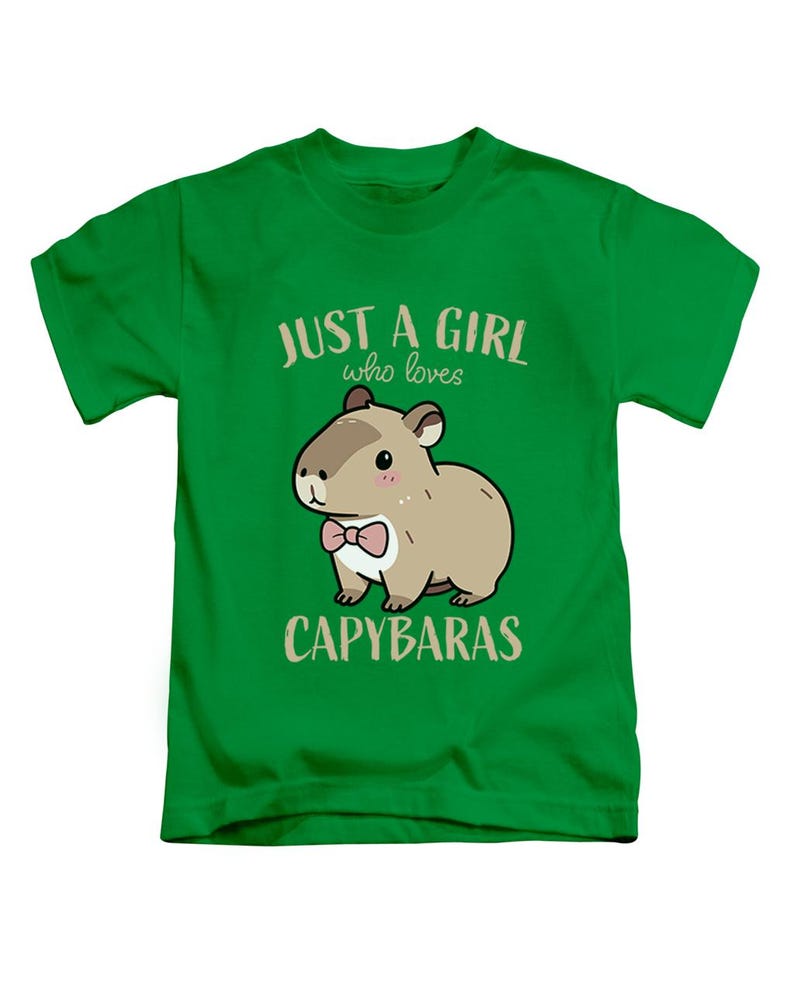 May include: Green t-shirt with the text "JUST A GIRL who loves CAPYBARAS". The shirt features a cartoon capybara wearing a pink bow tie. The capybara is brown with a white belly.