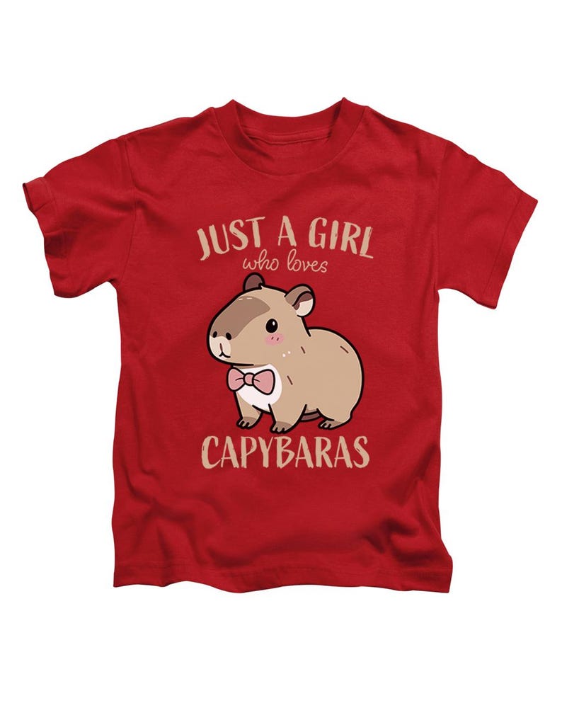May include: Red t-shirt featuring a cartoon capybara wearing a pink bow tie. The text "JUST A GIRL who loves CAPYBARAS" is printed above and below the capybara illustration. The shirt is made of a soft material.