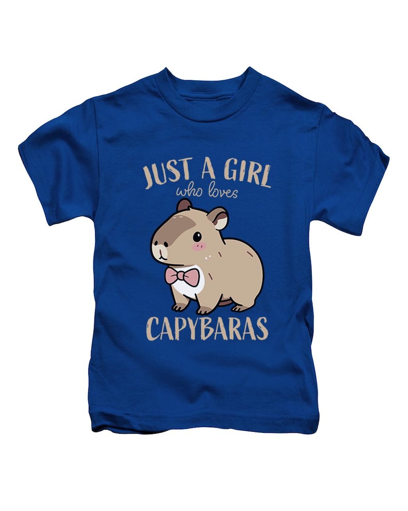 May include: Blue t-shirt with the text "JUST A GIRL who loves CAPYBARAS." The shirt features a cartoon capybara wearing a pink bow tie. The capybara is brown with a white belly and pink cheeks.