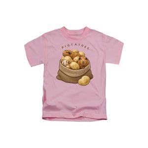 May include: A light pink short-sleeve t-shirt featuring a graphic of a burlap sack filled with brown guinea pigs and tan potatoes. The text PIGTATOES is printed in brown letters above the sack, with one additional potato resting in front.
