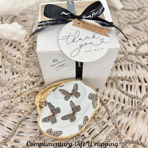 May include: A set of three ceramic mugs with a speckled, matte finish. The mugs are in shades of cream, light gray, and dark gray. Each mug has a simple, minimalist design and a rounded handle. The mugs are likely for coffee or tea.