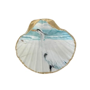 A coastal scallop shell decorative dish with a white egret bird ocean theme design. The shell is trimmed in bright gold painted edging.
