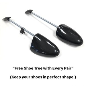 Pode incluir: Duas formas de sapato pretas com design de mola. As formas de sapato t&ecirc;m uma biqueira de pl&aacute;stico preta e uma haste de metal com uma pega. O texto "Free Shoe Tree with Every Pair" est&aacute; abaixo.