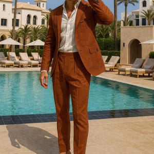 Pode incluir: Um homem veste um fato cor de ferrugem, com casaco e cal&ccedil;as a condizer, camisa branca e mocassins bege. O fato tem um aspeto texturizado. O fundo apresenta uma piscina e palmeiras.