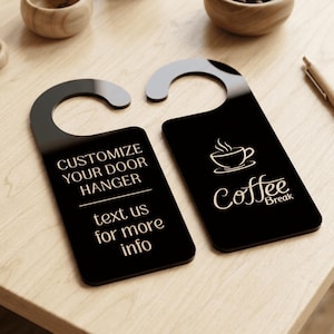 May include: Two black acrylic door hangers with rounded tops. One hanger features the text CUSTOMIZE YOUR DOOR HANGER and text us for more info in light lettering. The other hanger displays a graphic of a steaming coffee cup and the text Coffee Break.