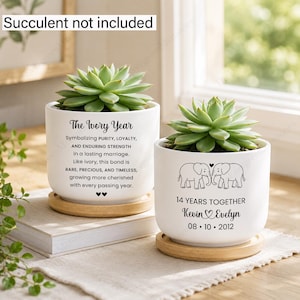 May include: Two white ceramic cylindrical planters with light wood bases, each holding a green succulent. The left planter features the text The Ivory Year and a poem about marriage. The right planter displays two elephants, 14 YEARS TOGETHER, the names Kevin and Evelyn, and the date 08 10 2012.
