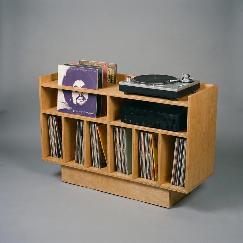 Light oak vinyl storage console with turntable shelf, amplifier space, album display, and organized LP compartments for a clean home audio listening room.