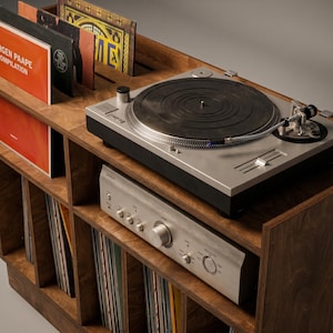 Close-up of Groove No.3 walnut record player console showing turntable placement, silver amplifier, layered plywood edges, record display slots, and vinyl storage below.