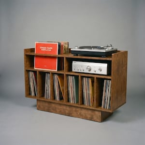 Angled front view of Groove No.3 walnut record player stand with turntable, silver amplifier shelf, front-facing album display, and six vertical vinyl storage compartments.