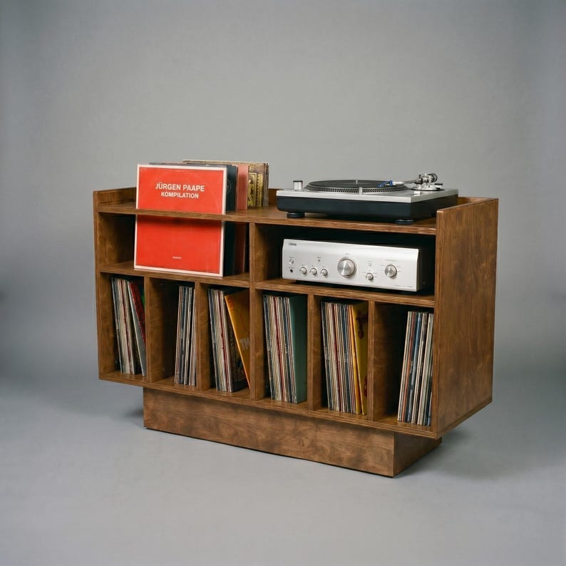 Angled front view of Groove No.3 walnut record player stand with turntable, silver amplifier shelf, front-facing album display, and six vertical vinyl storage compartments.