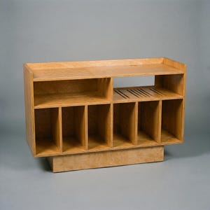 Empty Groove No.3 vinyl console in natural birch plywood, showing open shelves, six vertical record compartments, cable opening, and ventilation slots for audio equipment.