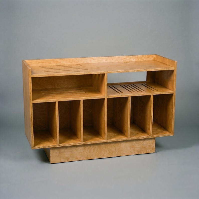 Empty Groove No.3 vinyl console in natural birch plywood, showing open shelves, six vertical record compartments, cable opening, and ventilation slots for audio equipment.